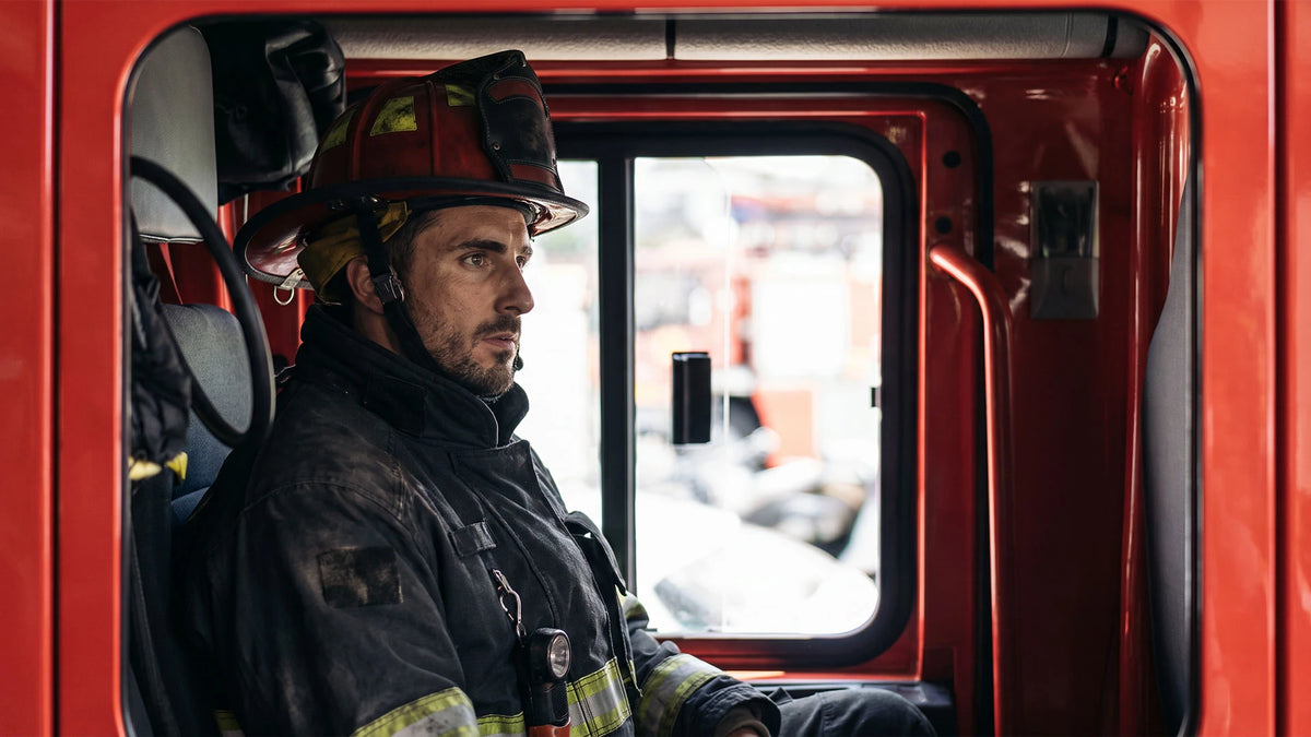 A firefighter seated in the cab of a fire engine