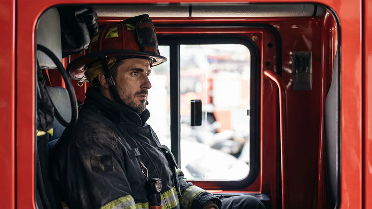 A firefighter seated in the cab of a fire engine
