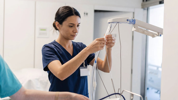 A nurse at a patient bedside on a bright ward