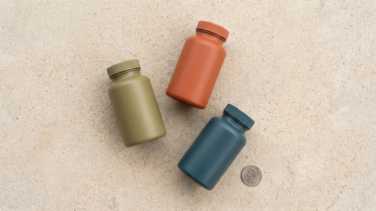 Three unlabelled bottles set well apart on a pale concrete surface with generous empty space around them.
