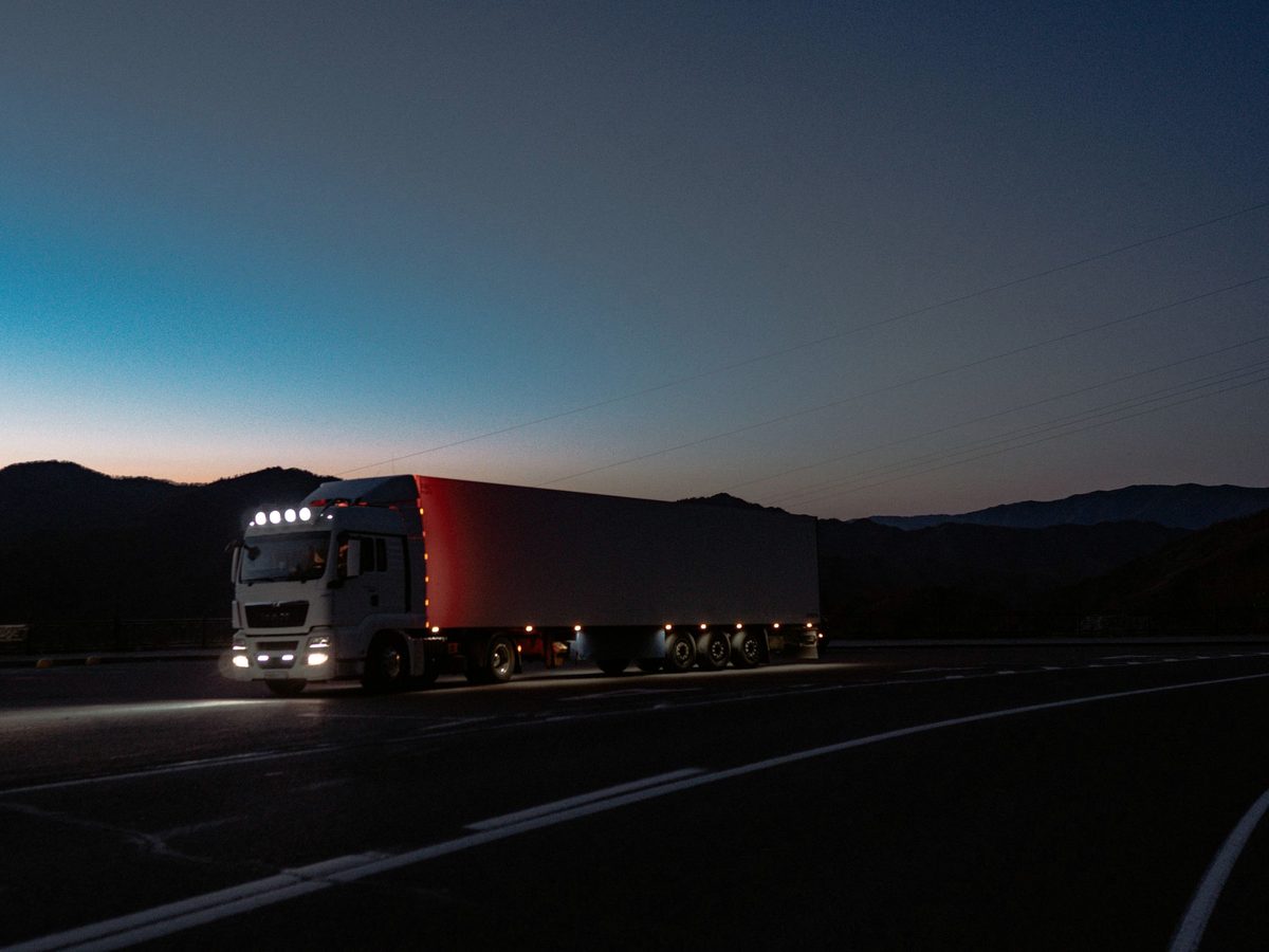 A tractor trailer on an open highway at first light